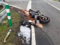 zdjęcie przedstawia zniszczony motocykl, który leży na drodze obok barier energochłonnych