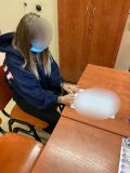 zdjęcie przedstawia siedzącą przy biurku kobietę, która ma na rękach zapięte kajdanki