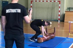 zdjęcie przedstawia salę gimnastyczną, na której Instruktor sprawdza kandydata do służby podczas wykonywania toru przeszkód.
