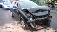 Na zdjęciu widać zgnieciony przód samochodu peugeot 206. Za samochodem widać policyjny radiowóz i karetkę pogotowia.