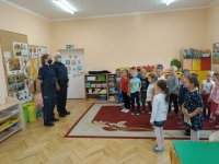 Na zdjęciu widać szkolną klasę, w której przed grupą uczniów stoi policjant i policjantka