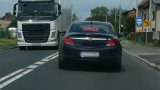 Na fotografii widać drogę dwukierunkową, po której nieoznakowany policyjny radiowóz mija się z samochodem ciężarowym. W tylnej szybie radiowozu  widać napis &quot;kontrola&quot;