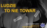 Zdjęcie czarno-białe. Na fotografii widać dwie tulące się do siebie kobiety, które do pleców mają przyklejone kartki z napisem &quot;na sprzedaż&quot; i  &quot;przecena&quot;. Tekst na zdjęciu: Ludzie to nie towar, zgłoś handel ludźmi.
