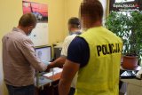 Na fotografii widać trzech mężczyzn - dwóch policjantów i zatrzymanego mężczyznę, któremu jeden z policjantów pobiera odciski palców. Odcisk palca sprawcy widać na monitorze komputera.