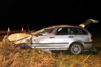 Na zdjęciu widać samochód marki BMW, który rozbity, stoi w przydrożnym rowie