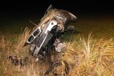Na zdjęciu widać samochód marki BMW. Auto leży na boku. Widać podwozie pojazdu i wyrwane przednie koło