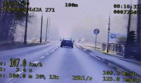 Na zdjęciu widać obraz z monitora policyjnego wideorejestratora. Widać tył samochodu osobowego jadącego drogą. Po bokach zdjęcia widać pomiar prędkości.