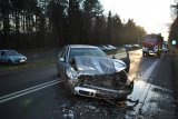 Na zdjęciu widać samochód marki Skoda Octavia. Auto stoi w poprzek drogi, ma zgnieciony przód. Z prawej strony zdjęcia widać wóz strażacki, przed którym stoi policjant i wykonuje pomiary specjalnym urządzeniem.