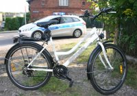 Na zdjęciu widać rower.  W tle widać policyjny radiowóz.