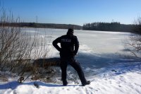 Na zdjęciu widać policjanta, który obserwuje zamarznięty akwen.