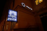Zdjęcie zrobione w nocy. Na zdjęciu widać wejście do budynku tarnogórskiej komendy. Przed wejściem widać podświetlony napis POLICJA