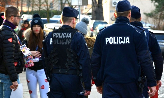 Na zdjęciu widać trzech, odwróconych tyłem policjantów. Obok nich stoi dziewczyna i chłopak, którzy na ubraniach mają naklejone serduszka WOŚP.