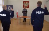 Na zdjęciu widać odwróconych tyłem nowo przyjętych policjantów podczas ślubowania, Policjanci mają uniesione do góry dwa palce. W tle zdjęcia widać Pierwszego Zastępcę Komendanta Powiatowego Policji w Tarnowskich Górach mł. insp. Sławomira Bylickiego, który odczytuje rotę ślubowania.
