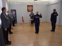 Na zdjęciu widać odwróconych tyłem ślubujących policjantów, przed którymi stoi  Pierwszy Zastępca Komendanta Powiatowego Policji w Tarnowskich Górach mł. insp. Sławomir Bylicki. Z lewej strony zdjęcia widać Kierownika Referatu Wykroczeń asp. szt. Benedykta Tomalkę, Komendanta Komisariatu w Zbrosławicach asp. szt. Lucjana Szmid,   Specjalistę Zespołu Kadr i Szkolenia asp. szt. Aneta Bartoszewską oraz Naczelnik Wydziału Prewencji kom. Piotra Skolika.