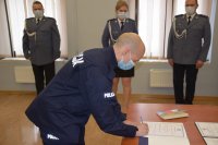 Na zdjęciu widać posterunkowego Piotra Koszyka, który składa podpis w obecności Pierwszego Zastępcy Komendanta Powiatowego Policji w Tarnowskich Górach mł. insp. Sławomira Bylickiego.