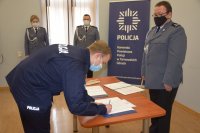 Na zdjęciu widać posterunkowego Dawida Tomalkę, który składa podpis w obecności Pierwszego Zastępcy Komendanta Powiatowego Policji w Tarnowskich Górach mł. insp. Sławomira Bylickiego.