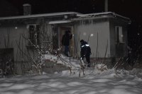 Na zdjęciu widać policjanta i pracownika socjalnego, którzy wchodzą do opuszczonego budynku