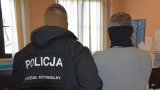 policjant ubrnay w czarna kurtkę z napisem Policja trzyma zatrzymanego