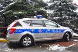 Na fotografii widać zaśnieżony policyjny radiowóz