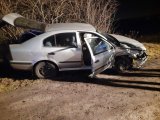Na zdjęciu widać rozbity samochód osobowy. Pojazd ma otwarte drzwi od strony pasażera oraz otwartą tylną klapę.
