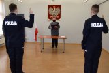Na zdjęciu widać Komendanta Bylickiego oraz stojących przed nim dwóch policjantów, którzy mają uniesione do góry palce i składają rotę ślubowania.