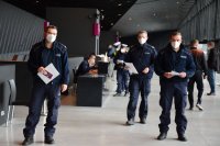 Na zdjęciu widać trzech policjantów idących korytarzem Szpitala Tymczasowego MCK w Katowicach.