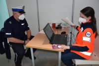 Na zdjęciu widać policjanta z drogówki, który siedzi przy biurku i rozmawia z lekarzem siedzącym po przeciwnej stronie biurka.