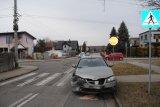 Na zdjęciu widać skrzyżowanie. Na przejściu dla pieszych, przed znakiem STOP  widać uszkodzonego nissana. W tle zdjęcia widać policyjny radiowóz oraz inne samochody.