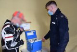 Na zdjęciu widać policjanta oraz zatrzymanego, pijanego kierowcę. Mężczyzna wdmuchuje powietrze do urządzenia służącego do badania stanu trzeźwości.