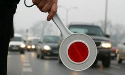 Na zdjęciu widać tarczę (tak zwany lizak policyjny)  służącą do zatrzymywania pojazdów. W tle zdjęcia widać przemieszczające się samochody.