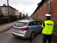 Na zdjęciu widać ustawiony w poprzek drogi policyjny radiowóz, obok którego stoi policjant