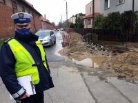 Na zdjęciu widać policjanta - dowódcę zabezpieczenia, który stoi obok dziury w ziemi, z której wydobywał się gaz