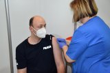 Na zdjęciu widać policjanta siedzącego na krześle oraz pielęgniarkę, która zakleja plastrem miejsce wkłucia igły.