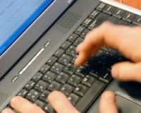 Na zdjęciu widać dłoń na klawiaturze laptopa