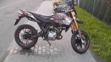 Na zdjęciu widać motorower zaparkowany na chodniku