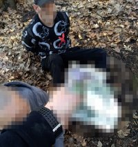 Na zdjęciu widać zatrzymanego mężczyznę siedzącego z zapiętymi kajdankami na ziemi.