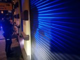 Na zdjęciu widać policjanta stojącego obok rolety antywłamaniowej.