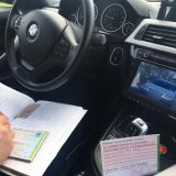 wnętrze policyjnego radiowozu. Policjant wypisujący dokumentację oraz druczek mandatu karnego