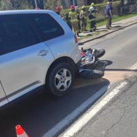 zdjęcie przedstawia tł szarego samochodu i motocykl leżacy na jezdni za samochodem