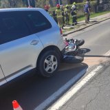 zdjęcie przedstawia tł szarego samochodu i motocykl leżacy na jezdni za samochodem