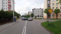 Na fotografii widać skrzyżowanie ulic, przy którym z prawej strony stoi znak ustąp pierwszeństwa. Na skrzyżowaniu widać dwa samochody biorące udział w zdarzeniu, a w tle policyjny radiowóz.