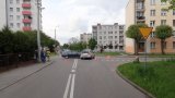 Na fotografii widać skrzyżowanie ulic, przy którym z prawej strony stoi znak ustąp pierwszeństwa. Na skrzyżowaniu widać dwa samochody biorące udział w zdarzeniu, a w tle policyjny radiowóz.