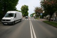 Na zdjęciu widać białego busa biorącego udział w wypadku. Za pojazdem znajduje się przejście dla pieszych, za którym widać dwa pozostałe, uszkodzone auta biorące udział w zdarzeniu.