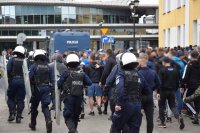 Na zdjęciu widać policjantów zabezpieczających grupę kibiców. Przed nimi jedzie armatka wodna
