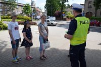 Na zdjęciu widać policjanta, który rozmawia z kobietą i  dwojgiem dzieci.