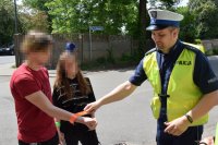Na zdjęciu widać policjanta, który zakłada odblask na rękę nastolatka