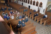 Na zdjęciu widać stojących w kościelnych ławkach uczestników mszy świętej.