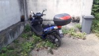 Na zdjęciu widać motorower zaparkowany za wysokim murem
