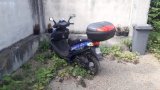 Na zdjęciu widać motorower zaparkowany za wysokim murem