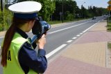Na zdjęciu widać policjantkę, która kontroluje prędkość pojazdów przemieszczających się w rejonie przejścia dla pieszych.